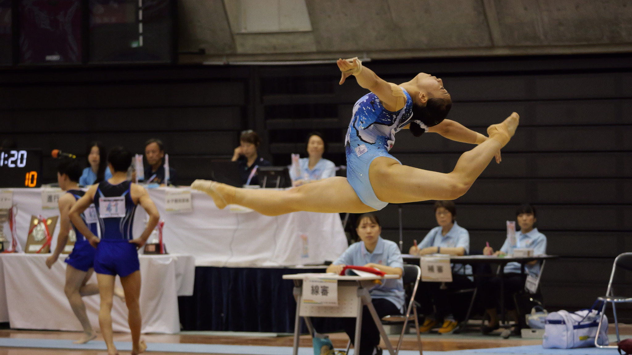 青いレオタードの選手が女子ゆかで跳躍する場面